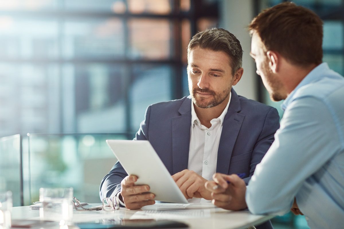 Zwei Berater besprechen die Unternehmensfinanzen am Tablet - 1516 Finance - Finanzpartner für B2B